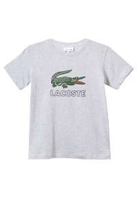 Harmaa puuvillainen t-paita, jossa vihreä krokotiilikuva ja alla mustalla kirjoitettu sana "LACOSTE", klassisella pyöreällä pääntiellä.