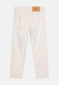 Jeans en coton couleur crème avec une coupe droite, dotés de deux poches arrière et d'une étiquette en cuir brun à la taille.