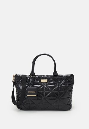 Black quilted tote bag with dual handles, detachable shoulder strap, and small attached pouch on light background.