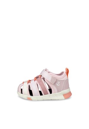 Różowo-koralowy sandał dla malucha z zakrytymi palcami, regulowanym paskiem, przewiewną tkaniną oraz miękką białą podeszwą zapewniającą komfort i wsparcie.