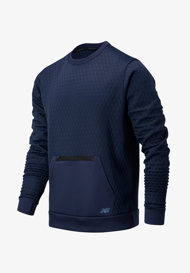 Sweat-shirt bleu marine à manches longues avec texture hexagonale, poche zippée avant, poignets côtelés et petit logo New Balance bleu clair sur le devant.