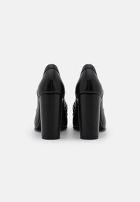 Scarpe con tacco alto nere in pelle liscia, con punta quadrata e tacco spesso. Presentano un design semplice senza decorazioni visibili.