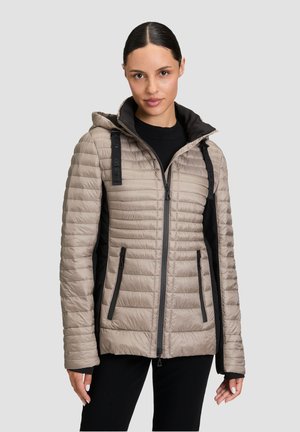 Giacca imbottita color beige chiaro con cappuccio, dotata di pannelli laterali neri, tasche con zip e una finitura liscia e texturizzata.