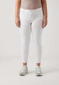 Jeans blancos ajustados con una cintura de altura media. La tela es suave y elástica, con un estilo de cinco bolsillos y un cierre de botón delantero.