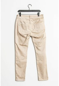 Pantalon beige en mélange de coton avec une coupe slim, doté de deux poches arrière et d'une finition nette. Suspendu à un cintre en plastique noir.