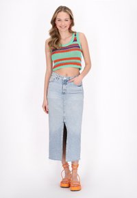Zöld horgolt crop top piros és kék csíkokkal; világoskék farmer szoknya elején hasítékkal; narancssárga platform szandál bokapántokkal.