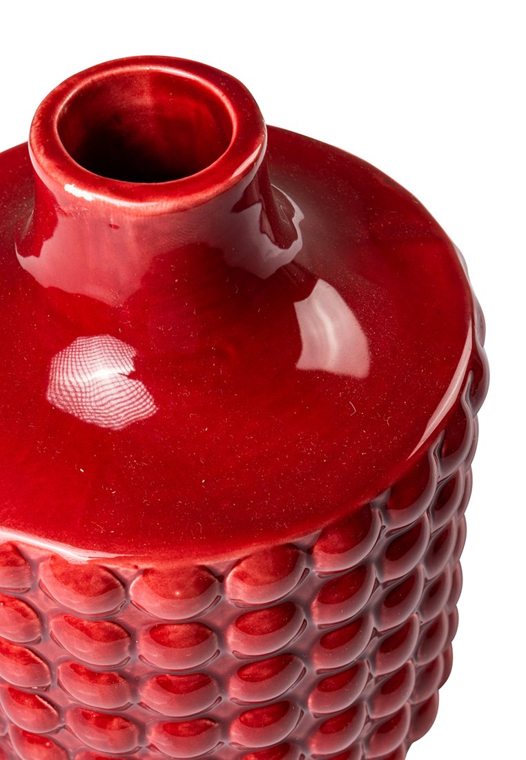 Vaso in ceramica rossa con finitura lucida, caratterizzato da una superficie texturizzata di cerchi in rilievo e un collo stretto.