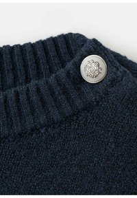 Ciemnoniebieski sweter z kołnierzem o ryżowym wzorze, z okrągłym, srebrnym guzikiem z dekoracyjnym detalem. Miękka dzianina.