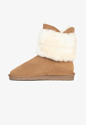 Tan ruskindsankelstøvle med en bred hvid faux fur-bund, rund tå og en struktureret gummisål for godt greb. Ingen synlig hardware eller mønstre.