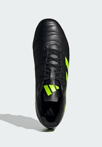 Zwarte voetbalschoen van textured leer, met limoen groene drie-strepen branding en een vetersluiting. Slank, gestroomlijnd ontwerp.