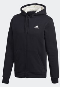 Sweat à capuche zippé noir Adidas avec poches avant, capuche à cordon doublée en polaire blanche et logo Adidas sur la poitrine gauche.