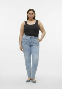 Svart topp med rund halsringning i tank stil, matchad med ljusblå högmidjade jeans. Modellen visar en enkel styling med diskreta blå klackar.