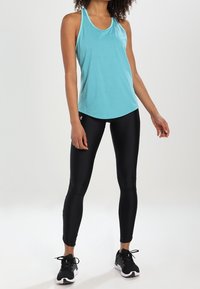 Ljusblått sporttop med racerback-design, matchat med svarta leggings. Sneakers har en strukturerad svart och vit sula.