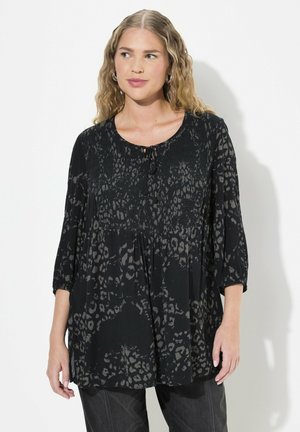 Blusa de estampado de leopardo negro con escote redondo, detalle de lazo y mangas de tres cuartos. Tela ligera y fluida con una sutil textura.