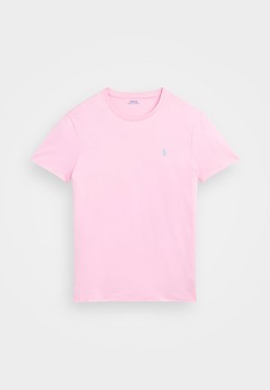 Jasnoróżowy t-shirt z krótkim rękawem i okrągłym dekoltem, z małym niebieskim wyszywanym logo na lewej piersi.