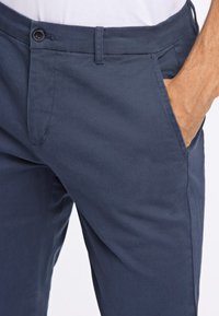 Navy blue pants made of smooth fabric, featuring a button closure, front pockets, and a straight-leg design.