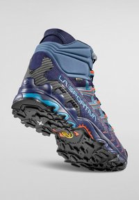 Wysokowydajne buty trekkingowe z granatową cholewką, oddychającą siateczką i pomarańczowymi akcentami. Posiadają solidną czarną podeszwę z bieżnikiem.