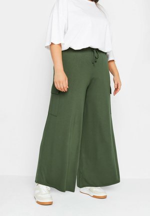 Groene wijde broek met een trekkoord in de taille, voorzien van twee zijzakken. Gepaard met een losvallend wit T-shirt en witte sneakers.
