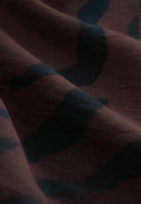 Tkanina tekstylna w ciemnym brązie z abstrakcyjnymi czarnymi wzorami, charakteryzująca się miękką, gładką fakturą i swobodnym układem.