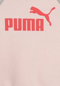 Ljusrosa sweatshirt med en stor röd "PUMA"-logotyp och en röd pantersilhuett, med grå detaljer på ärmarna. Mjuk textilstruktur.