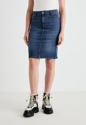 Denim pencil skirt in dark blue with front pockets and a fitted design. Paired with lace-up ankle boots featuring a chunky sole.