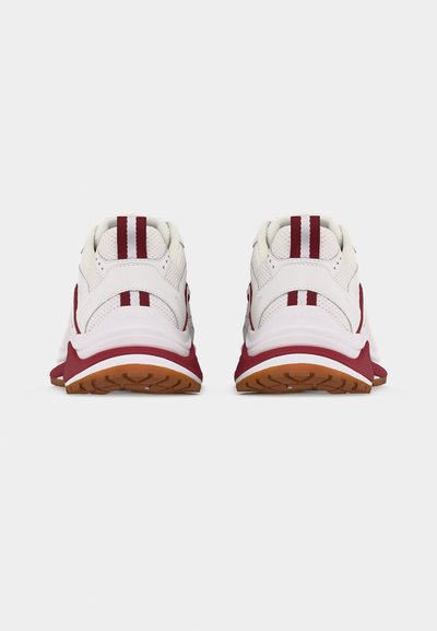 Λευκά και βουργουνδί αθλητικά παπούτσια, ορατά από πίσω, με υφασμένα πέλματα και διπλές κάθετες ρίγες στην ετικέτα της φτέρνας.