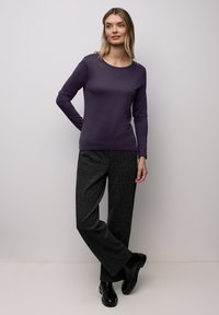 Long-sleeve purple top paired with dark gray textured wool trousers and black ankle boots; fitted top with a round neckline.