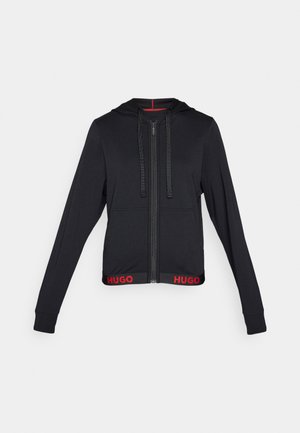 Hanorac negru cu fermoar și șnururi, are un tiv ribbed și un branding roșu "HUGO", mâneci lungi și o textură netedă a materialului.