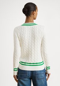 Camisola branca de malha com padrão de trança, gola e punhos canelados com riscas verdes e brancas, design justo e tecido texturado.