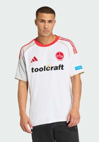 Biały strój sportowy z czerwonymi akcentami i złotymi wykończeniami. Zawiera logo z przodu oraz słowo "toolcraft". Krótkie rękawy i luźny krój.