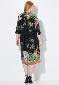 Schwarzes Kleid mit Dschungel-Tiermotiven, darunter Elefanten und Giraffen, mit kurzen Ärmeln und einem knielangen Saum, abgerundet mit einem einfarbigen braunen Besatz.