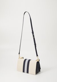 Gestreifte Schultertasche mit einem beigen Canvas-Körper, dunkelblauen Akzenten, goldfarbenen Beschlägen und einem verstellbaren Tragegurt; rechteckige Form mit flachem Boden.