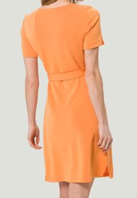 Sukienka z krótkim rękawem w pomarańczowym materiale z dopasowanym pasem i bocznymi rozcięciami, z okrągłym dekoltem i minimalnymi detalami szwów.