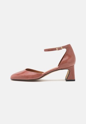 Chaussure à talons en cuir rose avec un bout arrondi et une bride à la cheville. Dispose d'un talon carré bas et d'une texture lisse et brillante.