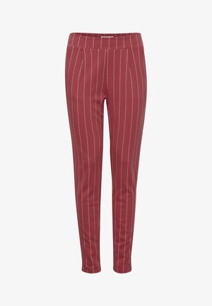 Röda avsmalnande byxor med vita vertikala ränder; tillverkade av ett mjukt, stretchigt material; har en elastisk midja. Inga fickor synliga.