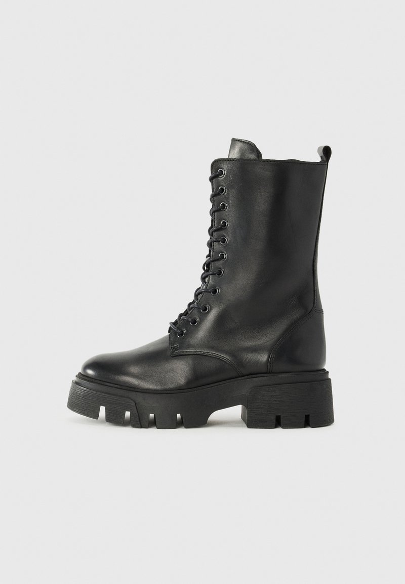 Botas negras de cuero con cordones y suela gruesa, acabado ligeramente texturizado y lengüeta en la parte posterior. Presenta ojales prominentes y costuras.