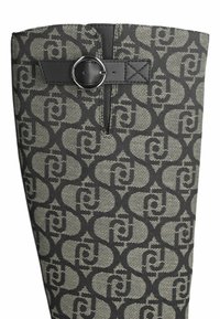 Stivale in tessuto nero e beige con motivo circolare, cinturino in pelle nera con dettaglio fibbia e superficie testurizzata.