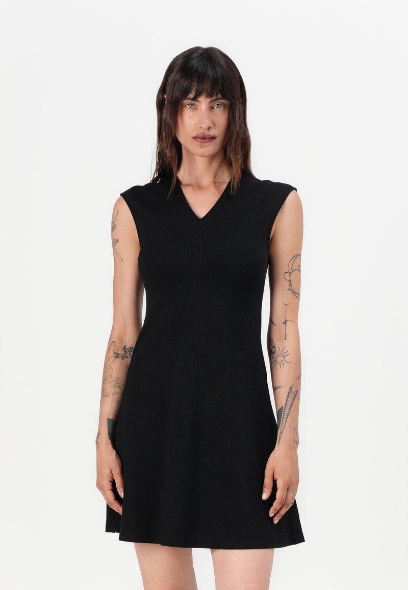 Musta hihaton mekko V-päällä, tiukka bodice ja levenevä hame. Valmistettu sileästä kankaasta, jossa on hienovaraista ompelusaumakuviota.