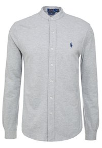 Vaaleanharmaa nappikauluspaita pystokauluksella, pitkät hihat ja pieni tummansininen Polo-logo vasemmassa rinnassa. Pehmeä kangaspinta.