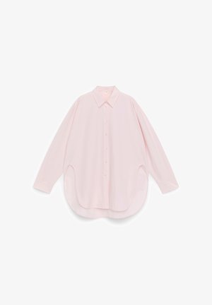 Light pink, long-sleeved shirt; features a classic collar, button closure, and curved hem with side slits. Soft fabric with a smooth texture.