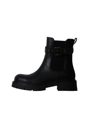 Bottine en cuir noir avec semelle épaisse, empiècement élastique latéral et bride de cheville avec boucle métallique sur fond blanc.