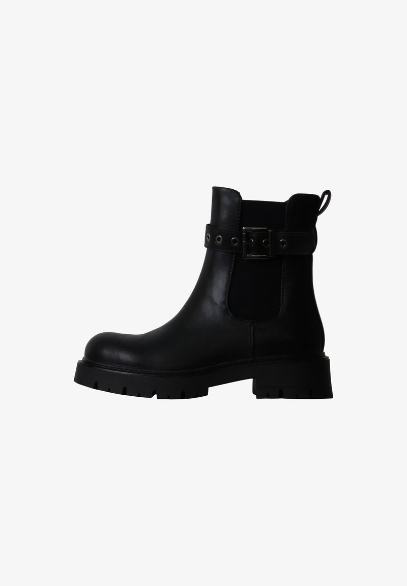 Bottine en cuir noir avec semelle épaisse, empiècement élastique latéral et bride de cheville avec boucle métallique sur fond blanc.