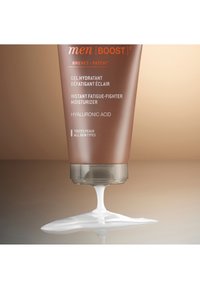 Bruine tube van vochtinbrengende crème met witte crème die uit de onderkant komt. Bevat tekst in meerdere talen, met de nadruk op hydratatie en hyaluronzuur.