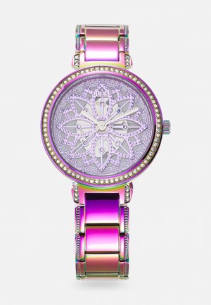 Montre ronde avec un cadran violet arborant un motif floral, entouré d'une lunette ornée de pierres précieuses. Bracelet en métal avec une finition irisée.