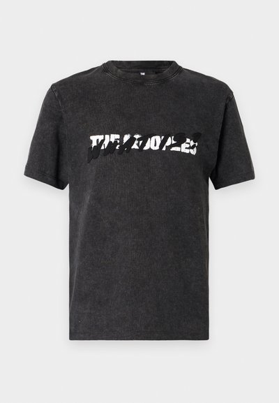 Camiseta de algodón negra con escote redondo, que presenta un audaz diseño gráfico blanco desgastado en el pecho. Manga corta.