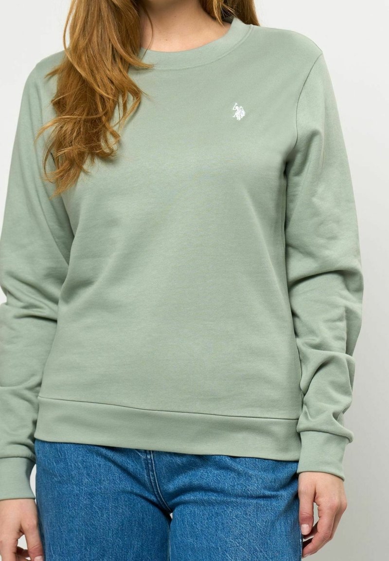 Sweat-shirt vert menthe en tissu doux, avec un col rond, des poignets côtelés et un petit logo brodé sur la poitrine.