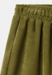 Olivengrønt frottéstof med elastisk, rynket taljebånd, som viser bløde, teksturerede løkker og plisserede folder.