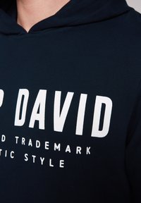 Granatowy dres z miękką teksturą. Posiada dużą białą blokową czcionkę "DAVID" oraz mniejszy tekst poniżej. W komplecie kaptur ze sznurkiem.