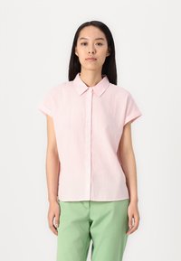 Camisa de botão de manga curta em rosa com riscas brancas. Tecido macio, com colarinho e bainha arredondada. Combinada com calças verde claro.