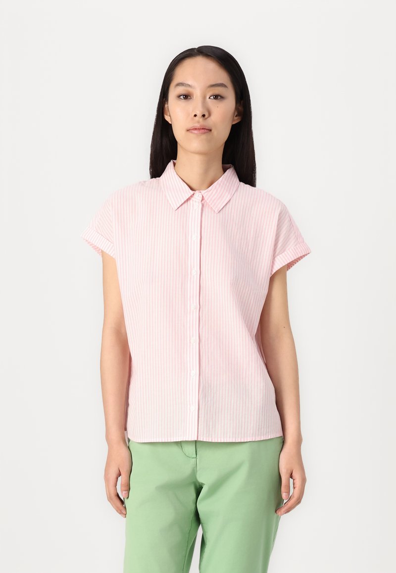 Camisa de botão de manga curta em rosa com riscas brancas. Tecido macio, com colarinho e bainha arredondada. Combinada com calças verde claro.